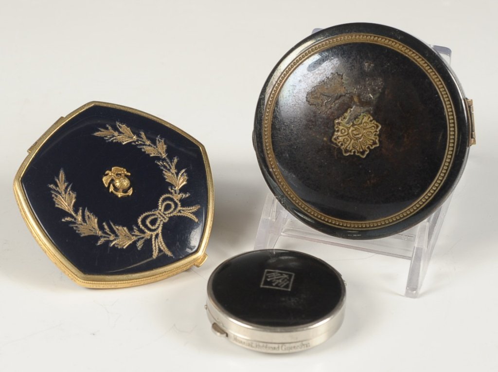 THREE VINTAGE ENAMEL COMPACTS: Navy blue enamel on goldtone duo compact with an emblem for the marines on top, Harriet Hubbard Ayers black enamel on silvertone compact with logo on top and a 1924 black enamel duo compact, measures 