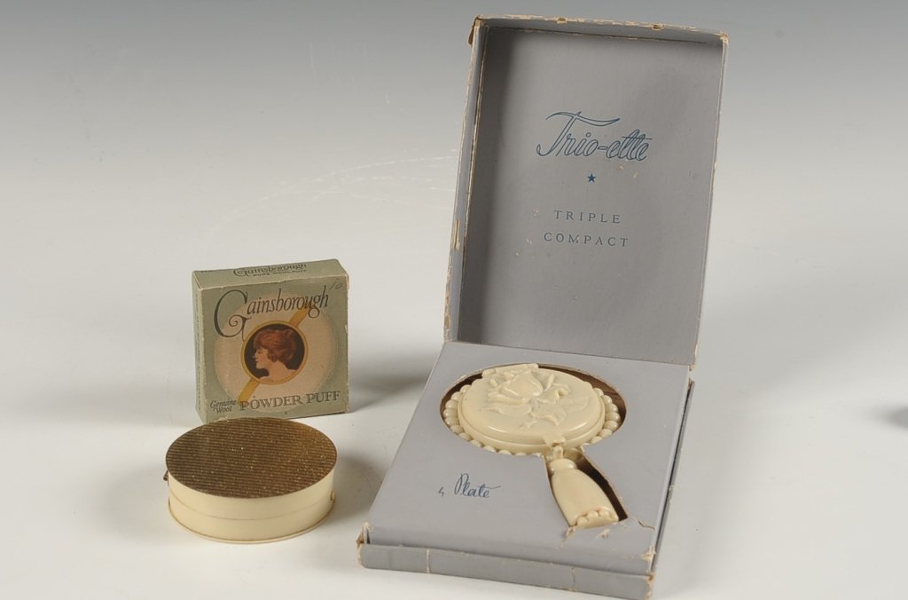PLATE COMPACT W BOX, GAINSBOROUGH PUFF IN BOX, MORE: Trio-ette plastic compact in a hand-mirror form, double-sided with branded puffs, rouge pan and mesh sifter, lipstick in the handle, complete and unused, fitted original box, inside mirror is cracked 