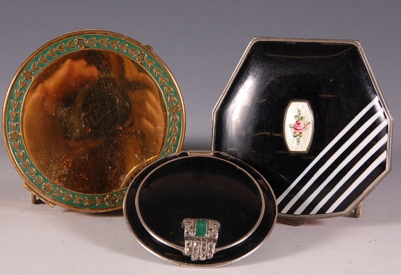 THREE ENAMELED COMPACTS: CJ Inc. compact with black and white enamel and guilloche on top measures 2.5 x 2.5 inches, very good. Black enamel compact with marcasite clasp, German, measures 2 inches, enamel is chipped on the ba