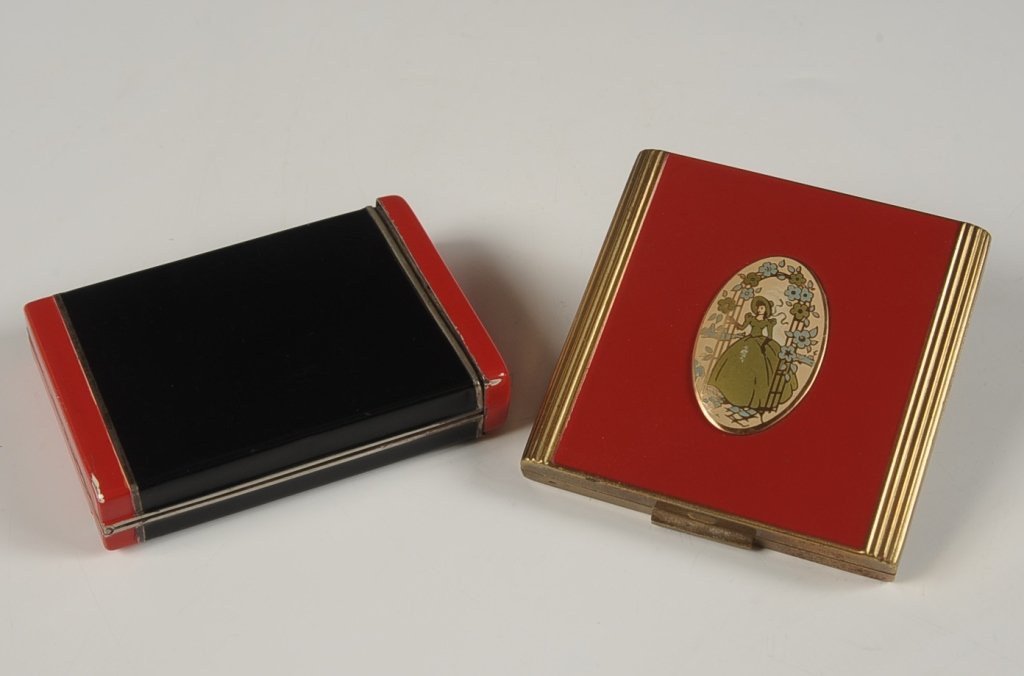 ENAMELED COMPACT AND MINIAUDIERE: Red on goldtone enameled compact with an enameled medallion of a woman on top, beveled mirror in the lid, hinged powder well with puff, unmarked, measures 2.75 inches, very good. Plus a red and black 