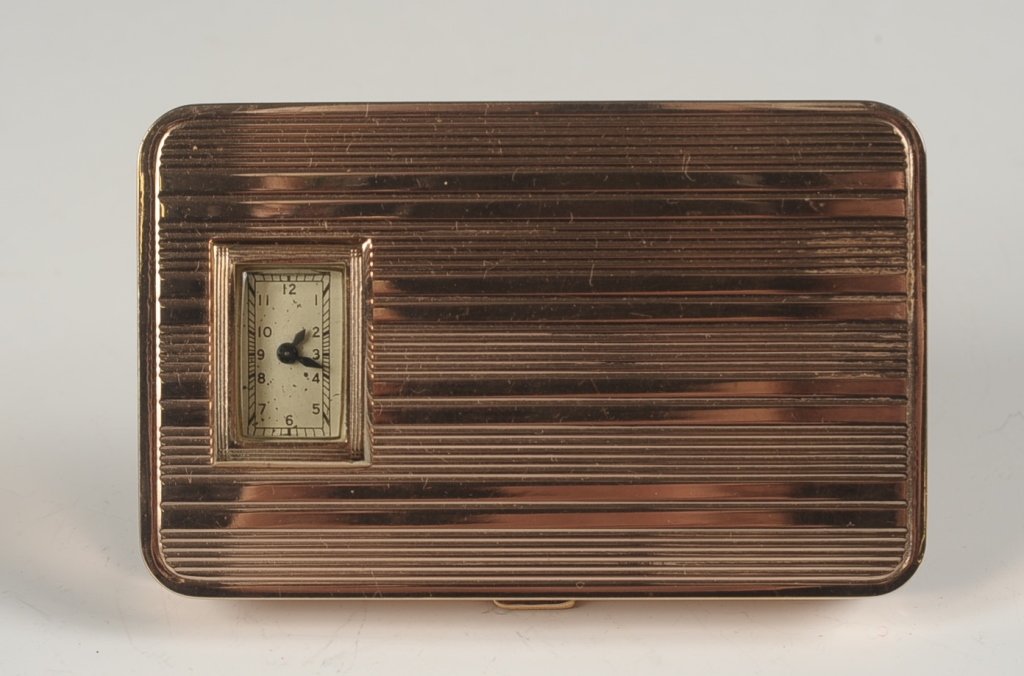 EVANS DUO COMPACT WITH A WATCH TOP: Goldtone duo compact with a peek through watch in the top, framed mirror and watch in the lid, rouge and powder wells in the base, marked on the powder well lid, measures 2.25 x 3.5 inches, includes f
