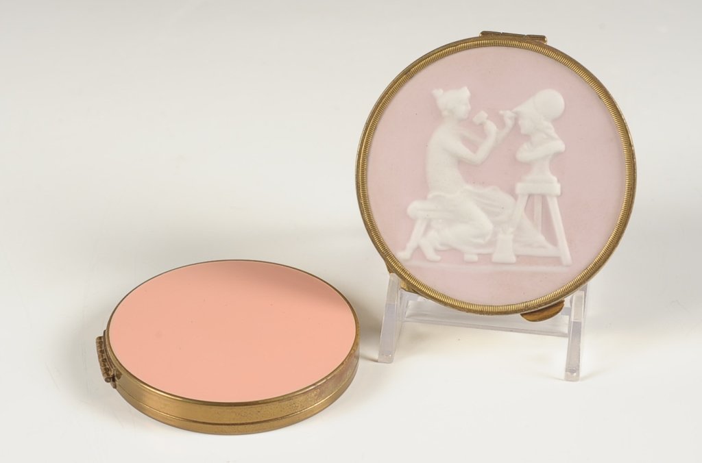 PINK WEDGEWOOD COMPACT & PINK ENAMEL COMPACT: Pink Wedgwood Jasperware compact with clear back, puff present, measures 2.75 inches. Pink enamel compact, mesh sifter and Volupte branded puff, measures 2.5 inches.