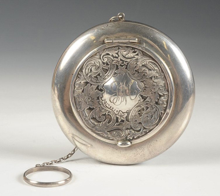STERLING COMPACT WITH REPOUSSE TOP: Chain handle with finger ring, framed mirror in the lid, marked on the bottom, puff present, measures 3 inches, weighs 1.65 ozt.