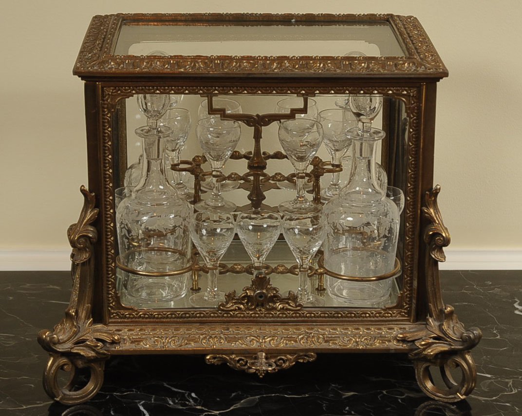 19TH CENTURY FRENCH GILT BRONZE TANTALUS LIQUOR CASKET: An ornate heavy bronze case, the front and top lift and fold to access the removable caddy set with engraved bottles having polished bottoms and matching engraved stems. The overall case measurements 