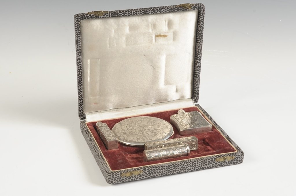 FIVE PC. CHASED STERLING VANITY SET: Includes a compact with a framed mirror, mesh sifter and puff, two perfume vials, and two lipsticks. Case measures 5.5 x 6.25 inches, with five pieces inside ranging in size from 2 inches in length up