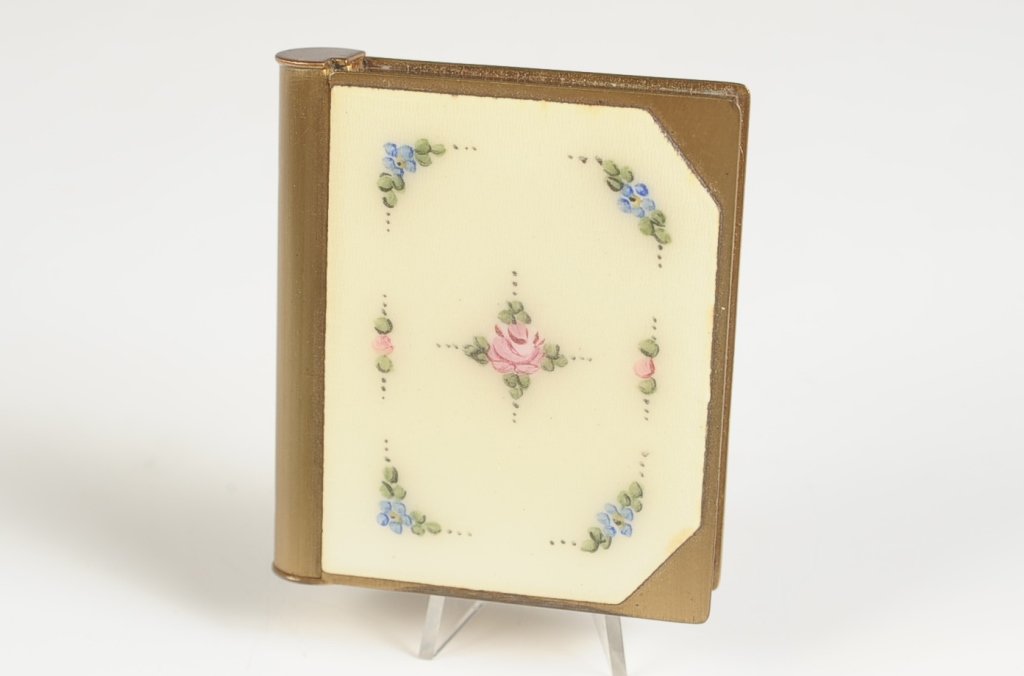 BOOK STYLE COMPACT WITH GUILLOCHE TOP: Lipstick in the spine, framed mirror in the lid, rouge well with pan, hinged powder well, unmarked, measures 2.5 x 2 inches.