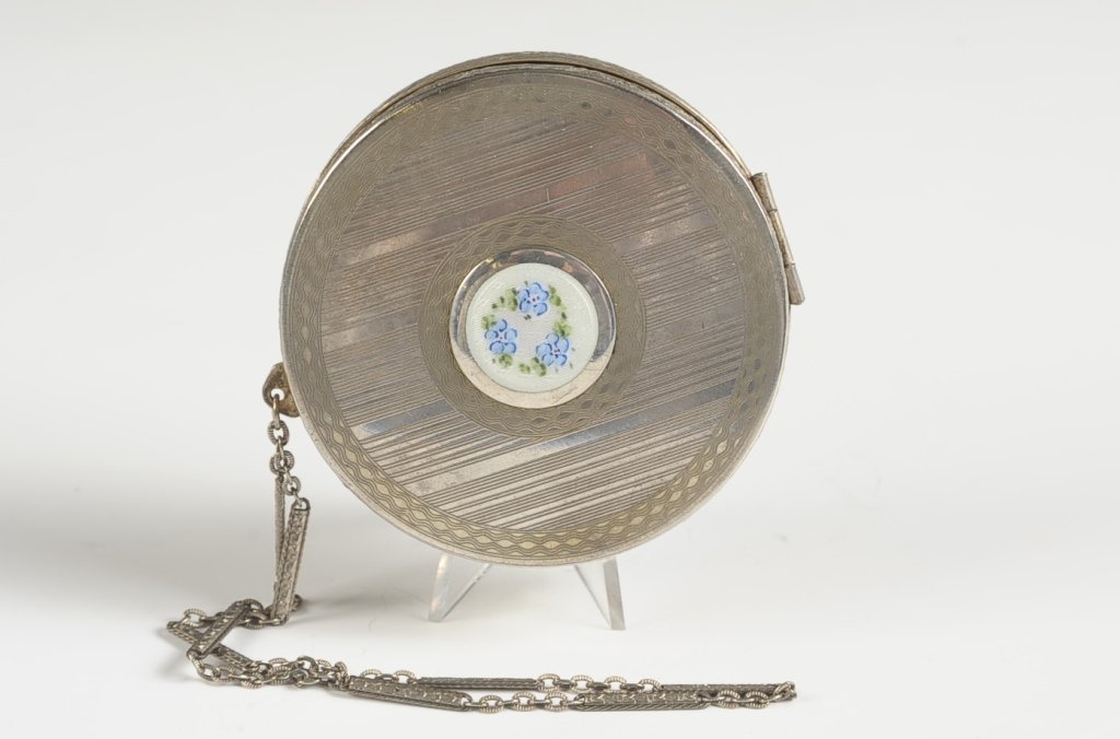 1923 DUO COMPACT WITH GUILLOCHE DECORATION: Chain handle, white guilloche center decoration with hand painted florals, hinged mirror over a rouge well with pan and puff, base holds a powder pan and puff, patent dated on the rouge well, monogram