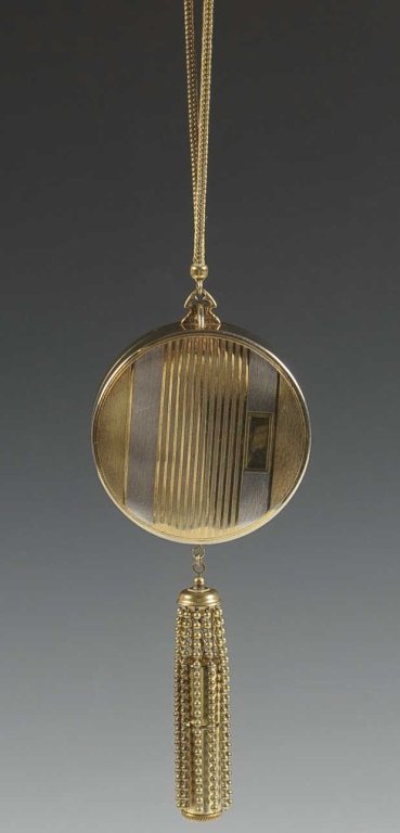 GILDED VANITY CASE WITH LIPSTICK TASSEL: Serpentine chain handle, chain tassel with a lipstick in the center, hinged mirror over a rouge in the lid with pan and puff, base with powder pan and puff, measures 11.5 x 2.5 inches from handle to t