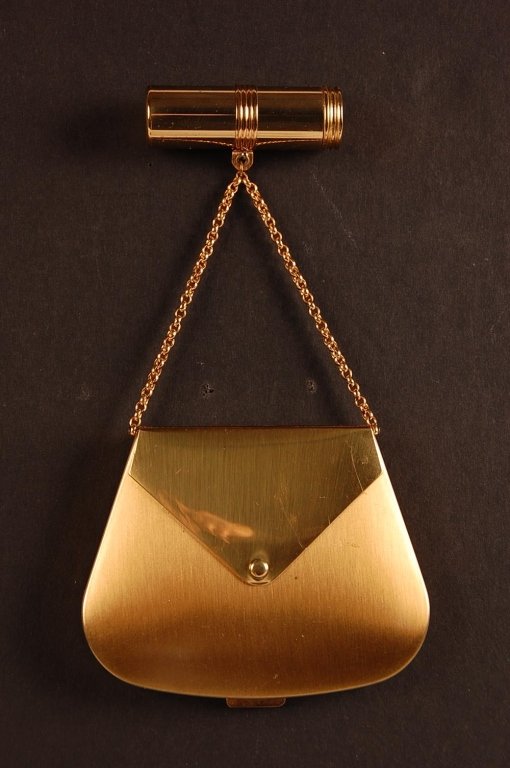 VOLUPTE PURSE-SHAPED COMPACT & A VANITY CASE: Volupte purse-shaped compact with a lipstick fob on the chain handle, locket style photo of a woman under the flap, framed mirror in the lid, hinged powder well with branded puff, marked on the powder