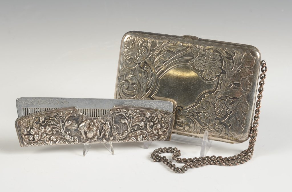 MINIAUDIERE WITH A THISTLE DESIGN AND A COMB CASE: Silvertone miniaudiere with an embossed thistle design top and bottom, chain handle, one side is lined with leather and has a leather pocket, other side has change holders, framed mirror and a hinged 