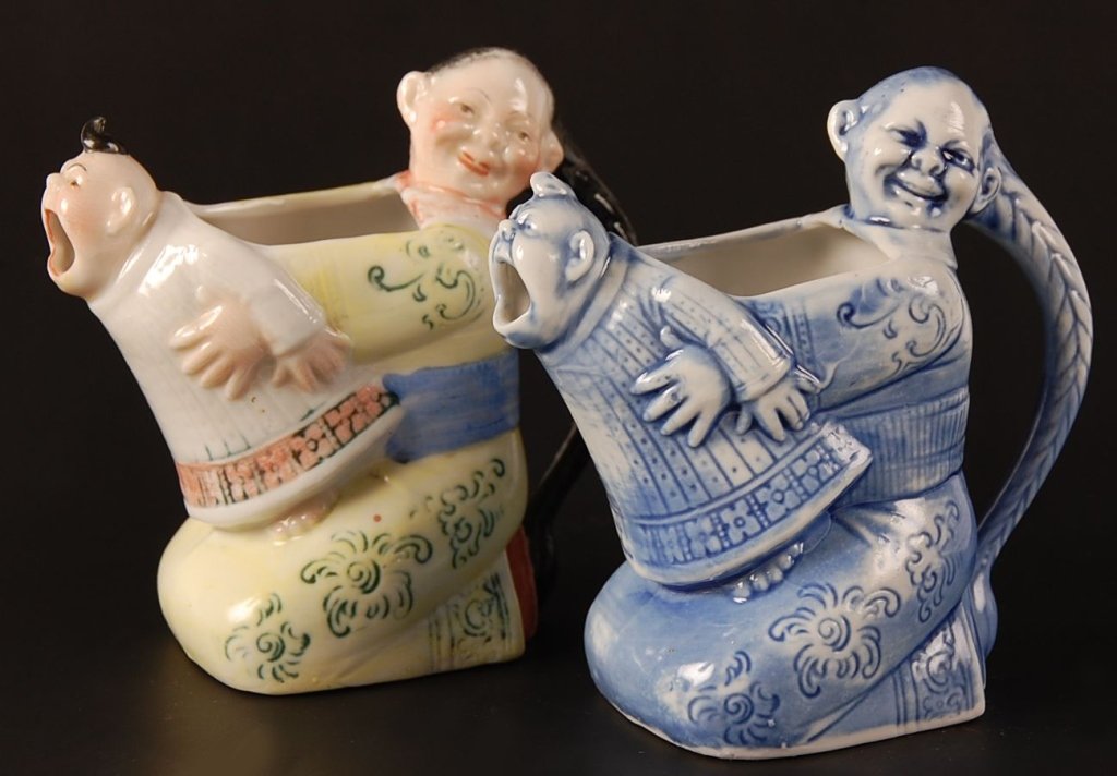 TWO SCHAFER & VATER CHINAMAN & CRYING BABY CREAMERS: Color and blue glazes, both with impressed marks, measure 3.5 x 4 inches each.Please note that this item will be shipped by our in-house shipping department and is subject to a 14 day return policy gu