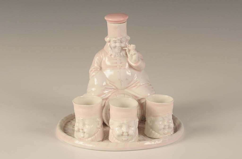 SHAFER & VATER 'SEDGWICK RYE' FLASK, TRAY & CUP SET: Pink and white glaze, sitting figural flask, oval tray, three figural Sedgwick cups, impressed marks on the flask and cups, five piece set ranging in size from 5 inches in diameter, up to 5.5 x 4.25 i