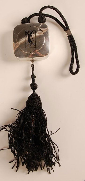 1922 STERLING DUO COMPACT WITH LIPSTICK TASSEL: Cord handle and tassel, lipstick fob in the tassel, etched design on the lid, rouge well in the top with mirror, pan and puff, base holds a mirror, pan and puff, marked on the bottom, lipstick and cor