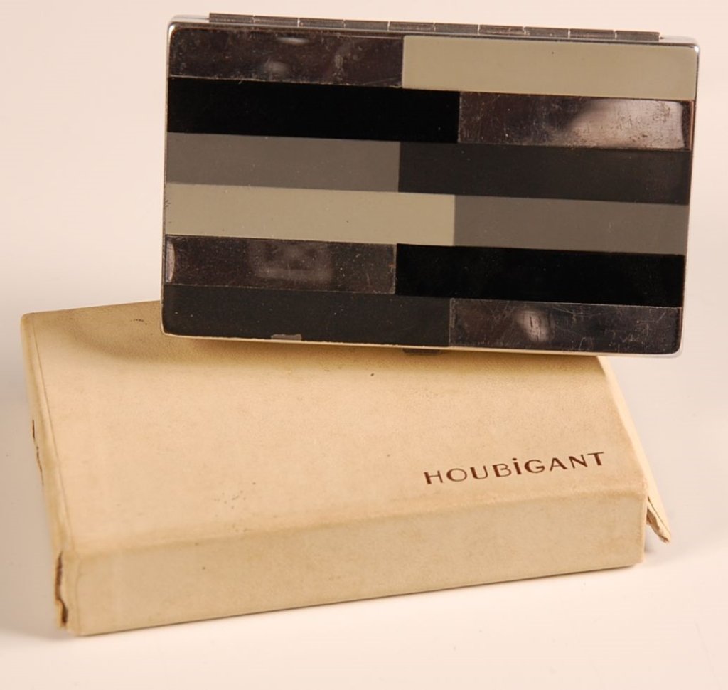 HOUBIGANT ENAMELED COMPACT WITH ORIGINAL BOX: Framed mirror in the lid, base holds pop up lipstick, rouge and powder wells with pans and branded puff, marked on the outside edge and on the lipstick, measures 2 x 3.25 inches.