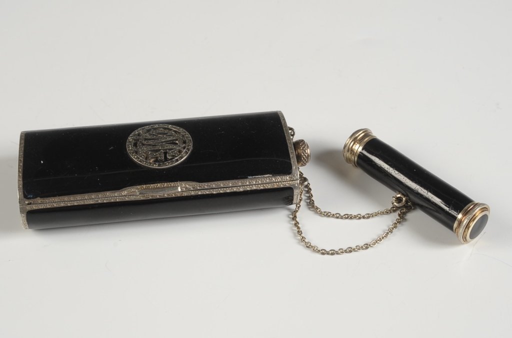 AUSTRIAN STERLING & ENAMEL BOLSTER-SHAPED VANITY: Black enamel on sterling vanity case with a lipstick fob, marcasite monogram on the top, chain handle, perfume flask at the top, framed mirror in the lid, powder and rouge wells in the base with pans,