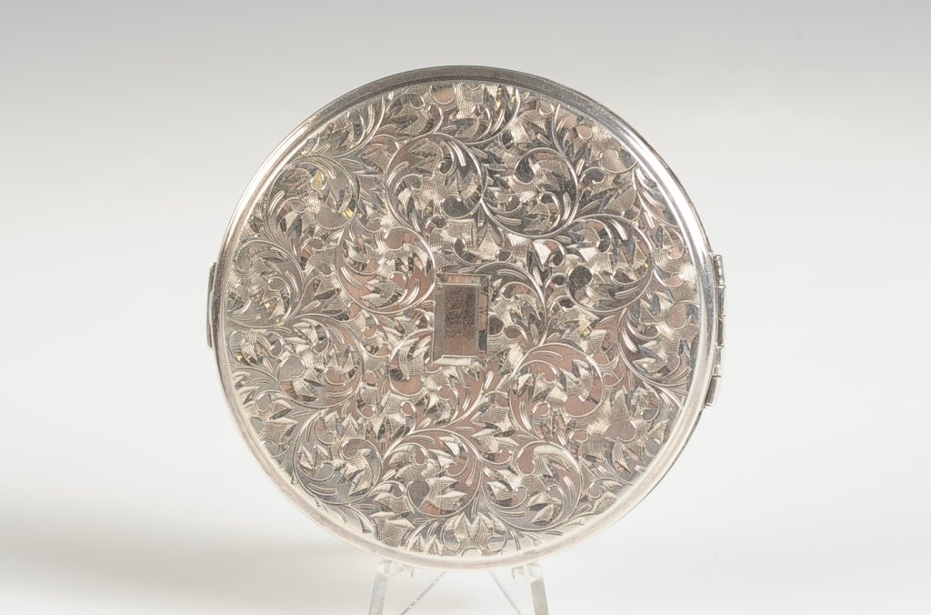 STERLING IMK QUEEN STAR HAND-CHASED COMPACT: Beveled mirror in the lid, hinged powder well, mesh sifter, marked on the base and back, branded on the powder well lid, measures 2.75 inches, weighs 2.75 ozt.