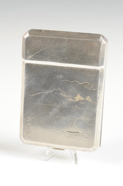 STERLING VANITY CASE WITH A JAPANESE THEME, SIGNED: Hand-chased design of Mount Fuji and a Japanese temple, signed on the back, framed mirror in the lid, base holds a pop-up lipstick with a heart push-up button, hinged powder well with mesh sifter and 