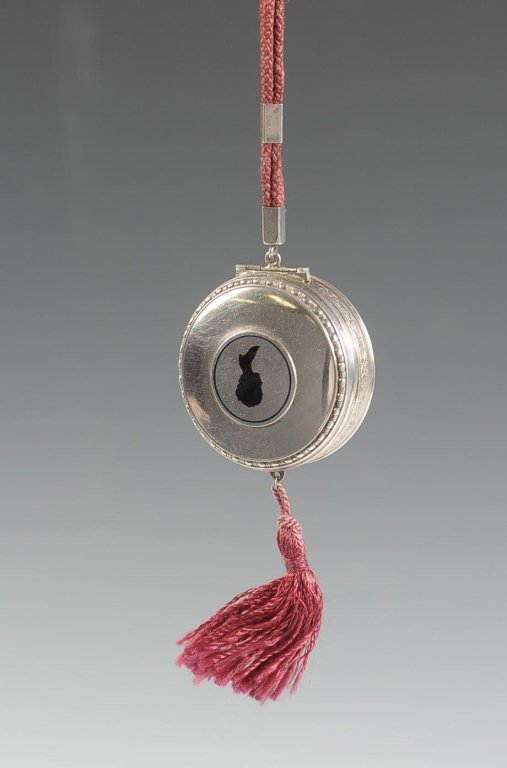 STERLING DUO COMPACT WITH WOMAN'S SILHOUETTE: Cord handle and tassel, hinged double-sided mirror divides the two wells, marked on the rim, weighs 1.5 ozt., measures 2 inches.