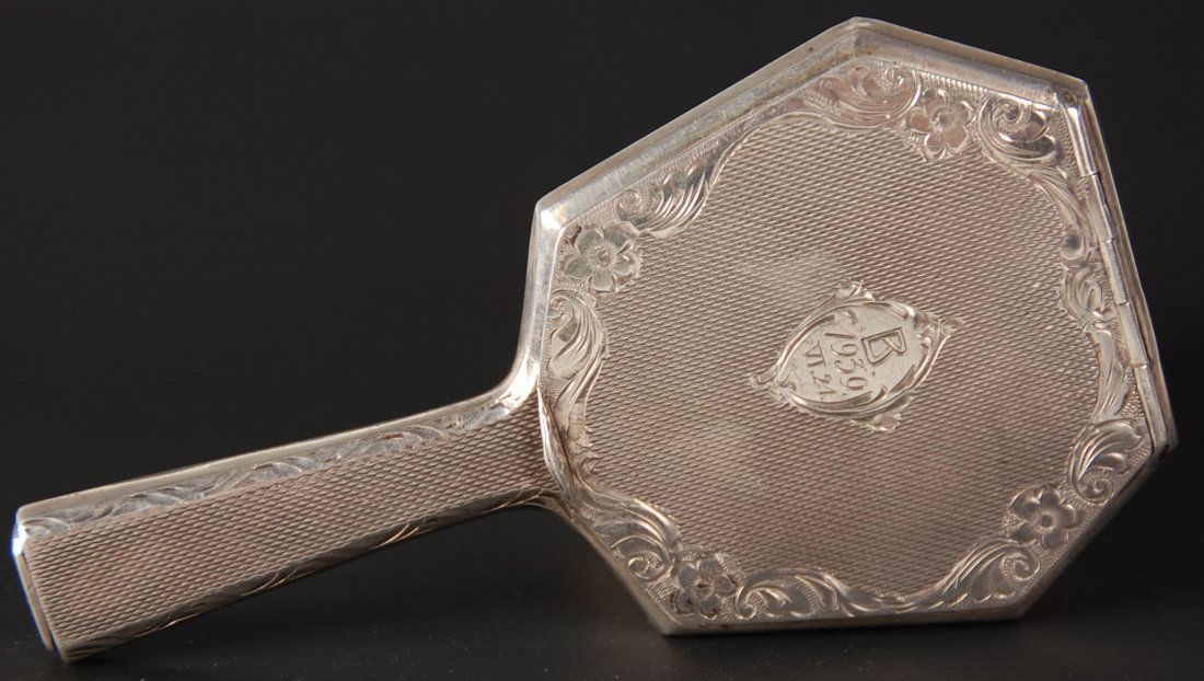 1939 .800 AUSTRIAN SILVER HAND MIRROR COMPACT: Hand chased designs on .800 silver with lipstick in the handle, monogrammed on the compact lid 'B 1939 VT.24', beveled mirror on the reverse, measures 4.5 x 2.5 inches, weighs 1.5 ozt. without the mir