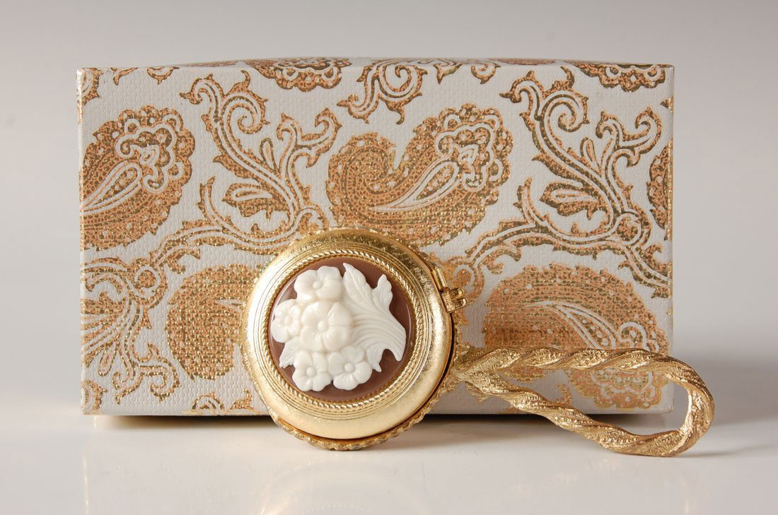 VINTAGE REVLON HAND MIRROR COMPACT W ORIGINAL BOX: Goldtone hand mirror compact with a plastic flower decoration on the top, mirrored lid over a powder well with branded puff, powder pan and paper label, mirror on the reverse, includes the original br