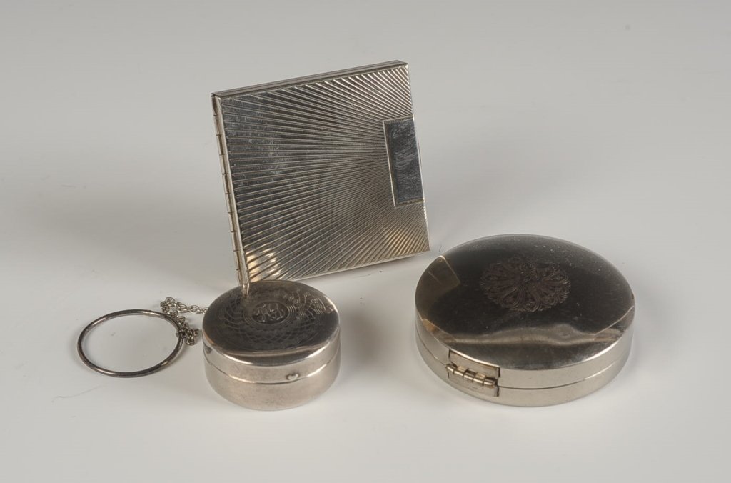 TWO STERLING COMPACTS, PLUS ANOTHER COMPACT: Small sterling compact with finger ring measures 1.25 inches, weighs .5 ozt. Volupte sterling compact with mirrored lid and metal insert powder well, measures 2 inches, weighs 1.85 ozt. Plus a silvert