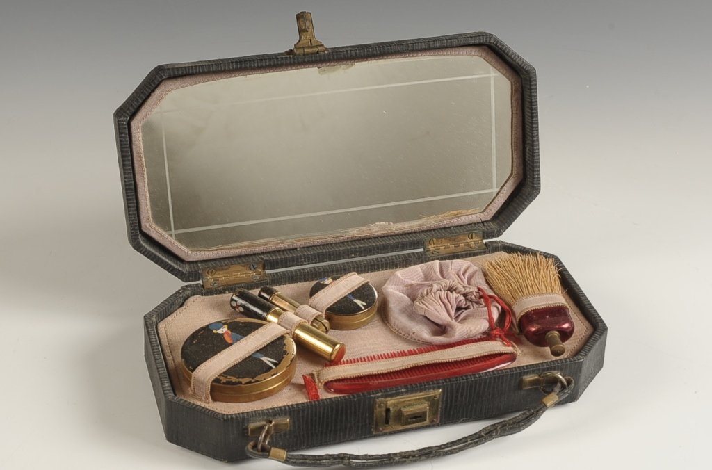 FOUR PIECE ENAMELED VANITY SET WITH LEATHER CASE: Vanity set includes an enameled compact, rouge, lipstick, larger perfume or lipstick, plastic comb and a whisk, leather case with a mirror in the lid, vanity set inserts into an upper divider over sto