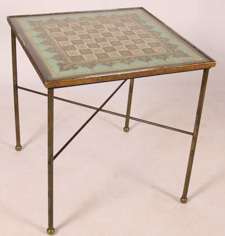 AN EGLOMISE REVERSE PAINTED GAMES TABLE CIRCA 1920: Square-form brass banded top, fleur-de-lis banded pattern on a mint ground, raised on four tubular brass legs terminating in ball feet and joined by a high X-stretcher. Measures 26 x 24 x 24 inches.