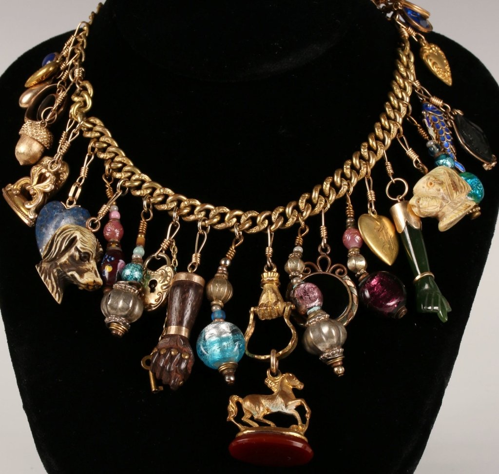 COLLECTION OF VICTORIAN AND OTHER FOBS, CHARMS AND: Including small love token, small faceted colored stones, enamel reticulated fish, black glass cameo, ivory dogs head, green hardstone hand, various heart lockets, beads of later vintage, hand and hor