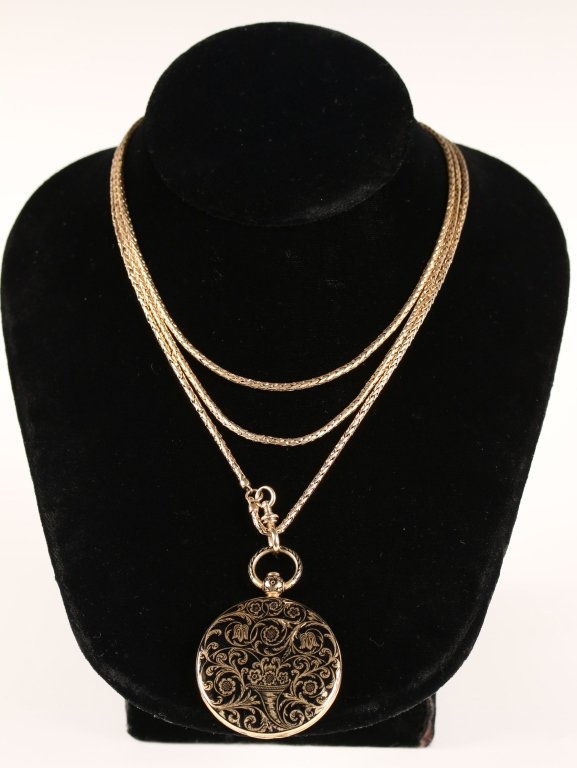 CIRCA 1838 GOLD LOCKET WITH BLACK ENAMEL AND CHAIN: A pocket watch form gold locket with black enamel and push button catch. Inside is an engraved memorial with the date of 1838. Included is a 27 inch woven gold link chain that tests around 15k gold. W