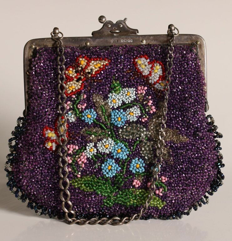 ANTIQUE BEADED PURSE WITH A STERLING FRAME: Glass beads with a butterfly design on both sides, short beaded loop fringe along the bottom, sterling frame, clasp and chain with British hallmarks, satin lining, measures 5.5 x 5.5 inches, with a 5.