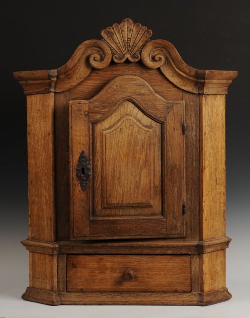 18TH CENTURY SCANDINAVIAN OAK HANGING CABINET: With shell carved finial between scrolling pediment, arched door and a single drawer. Measures 34 x 27 x 13 inches.