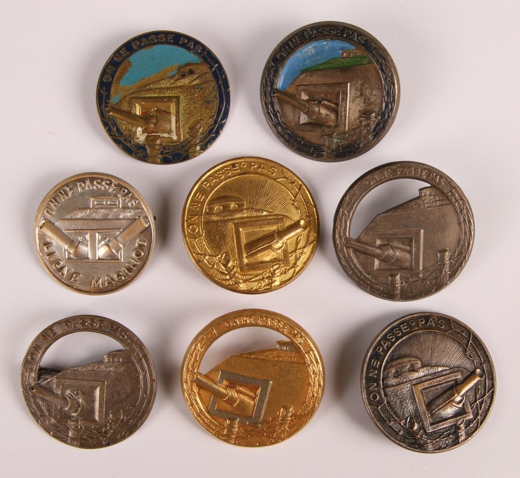 WWII FRENCH VERDUN/MAGINOT LINE PATRIOTIC BADGES: Various stamped and cast 'On Ne Passe Pas' pinback badges, two with painted details, two with gilded finish. One with double barrel, two point opposite direction from the others. Approximately 1-3/8 i
