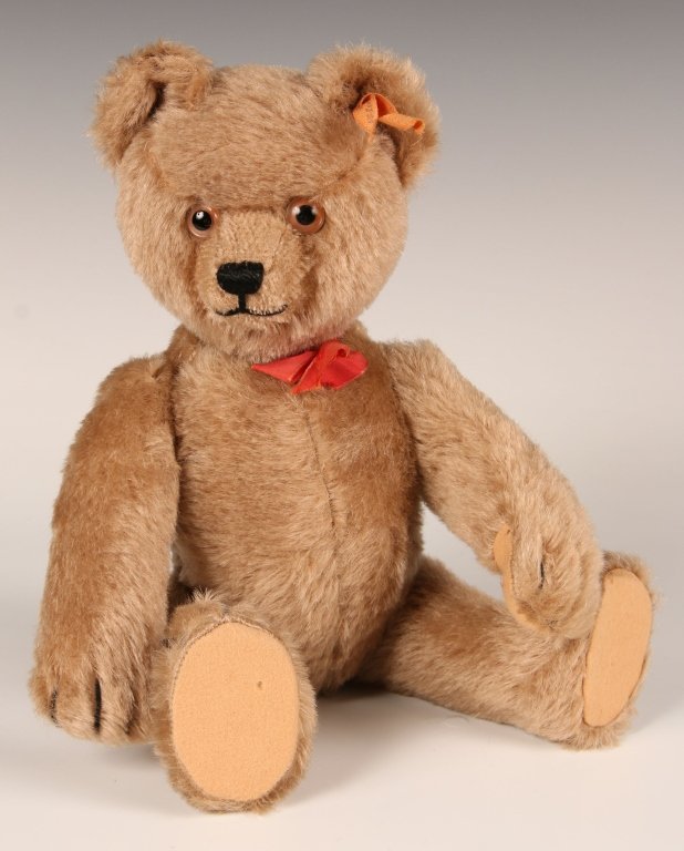 CIRCA 1950 STEIFF YES-NO TEDDY BEAR: Yes-No mechanism in the tail moves the bear's head, hug-me growler in the stomach, glass eyes, excelsior stuffing, U.S. Zone Germany ribbon in the ear, no button, measures 14 inches (36 cm) standing.