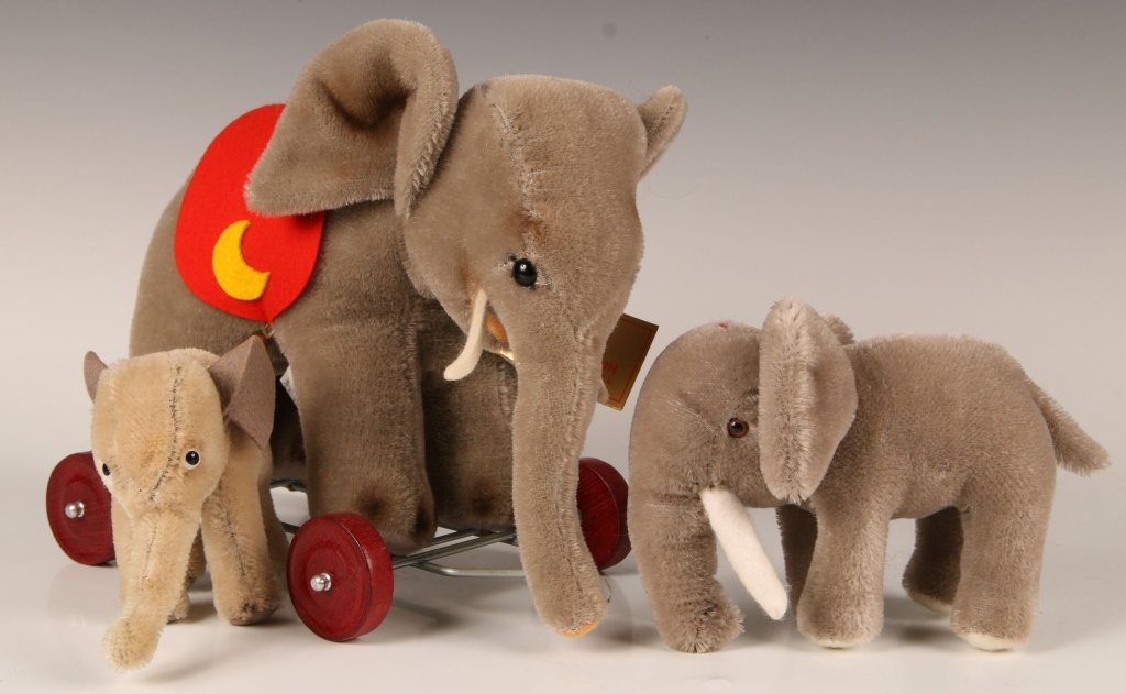 HERMANN ORIGINAL STUFFED ELEPHANT, PLUS TWO MORE: Hermann Original elephant toy on wheels, 310/20, felt saddle and bells, measures 8 x 10 inches. Merry Thought elephant, measures 4.5 x 8 inches. And an unmarked stuffed elephant, measures 4 x 5.5 inch