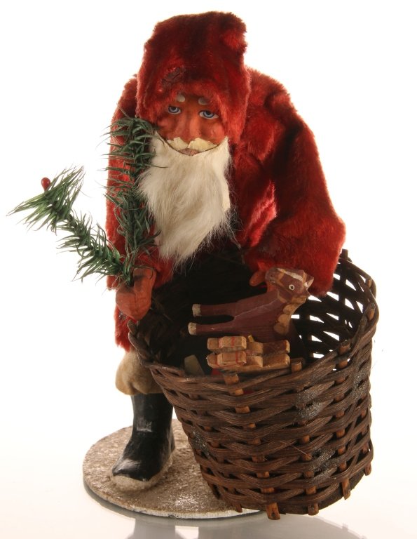 C. 1900 GERMAN PAPIER MACHE FATHER CHRISTMAS SANTA: Santa Claus and basket of toys, white fur beard, red felt coat and fur trimmed details. Measures 9 x 5.5 inches.