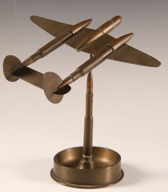 WWII TRENCH ART ASHTRAY WITH AIRCRAFT: Trench art made from part of a 1940 dated round and smaller calibers. With a removable B-25-like plane on a pedestal. Measures 7.5 x 6.5 x 8.5 inches.