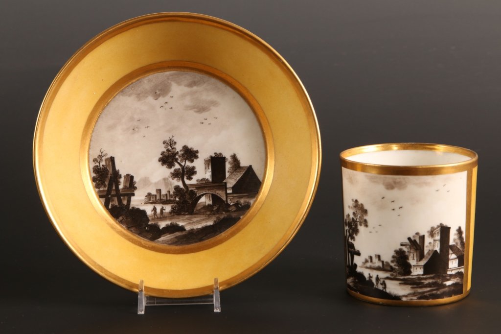 19TH C. CONTINENTAL PORCELAIN CABINET CUP & SAUCER: With en grisaille decoration. Unmarked. Cup measures 3.5 X 4.25 inches including the handle, and the saucer measure 1.5 x 7 inches in diameter.