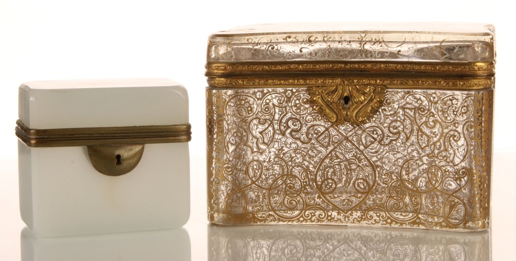 TWO GLASS JEWELRY CASKETS: Including a French, white opaline box with brass mounts and a colorless glass box with bronze mounts and gold tracery. Two pieces with the largest piece that measures 4.25 x 6.25 inches, and the small