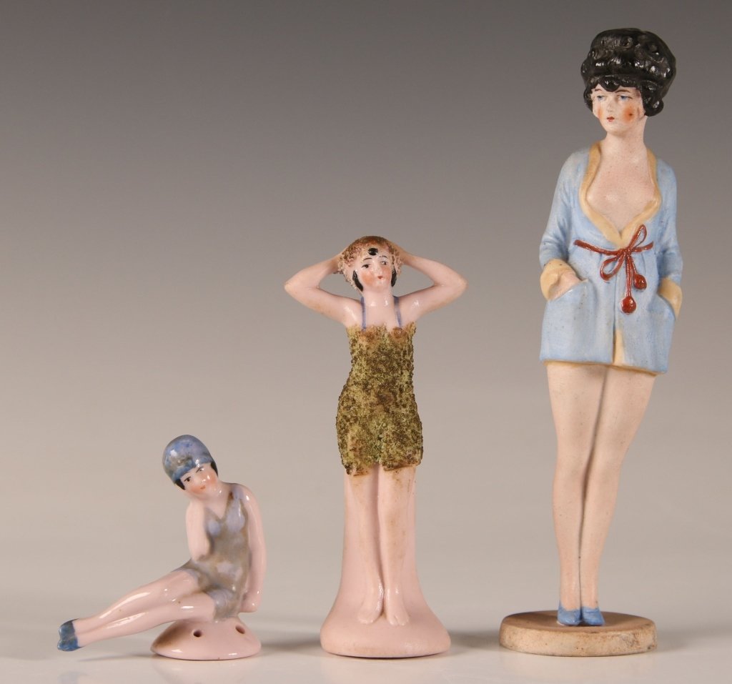 THREE GOOD GERMAN BISQUE BATHING BEAUTIES: Including a taller bisque figure with black hair and robe open at the breast signed Germany and mounted in an unusual manner to a porcelain base also signed Germany, a bathing beauty In swimsuit depic