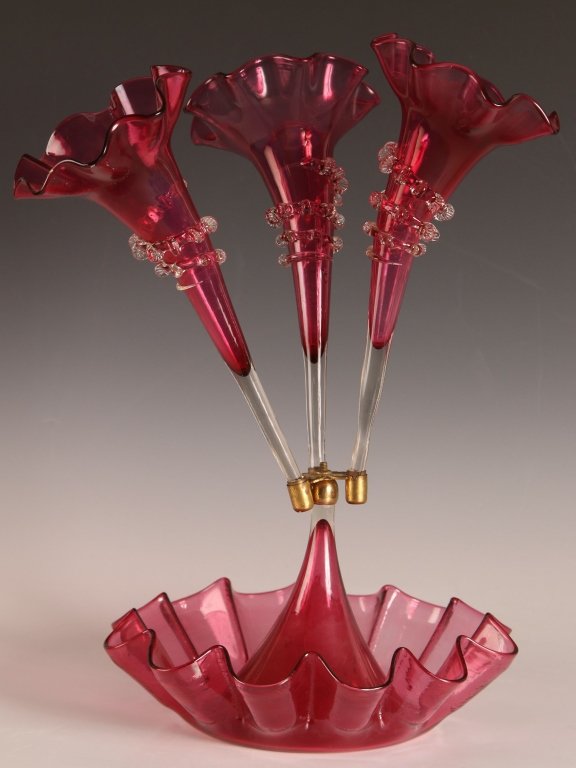VICTORIAN CRANBERRY THREE LILY EPERGNE: Each cranberry lily with applied rigaree. Measures 16.5 x 10.5 inches. We ship in-house for all but very large and or very fragile items and some international shipments.