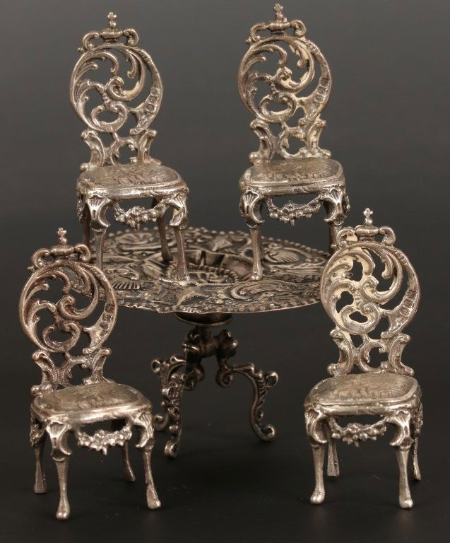 MINIATURE 19TH C. DUTCH ROCOCO TABLE AND CHAIRS: Rococo style tilt top table with repousse decoration and Dutch .800 silver hallmarks, measures 1.75 x 3 inches. Plus four rococo style chairs fully hallmarked and measuring 2.25 x 1 inches. We ship in