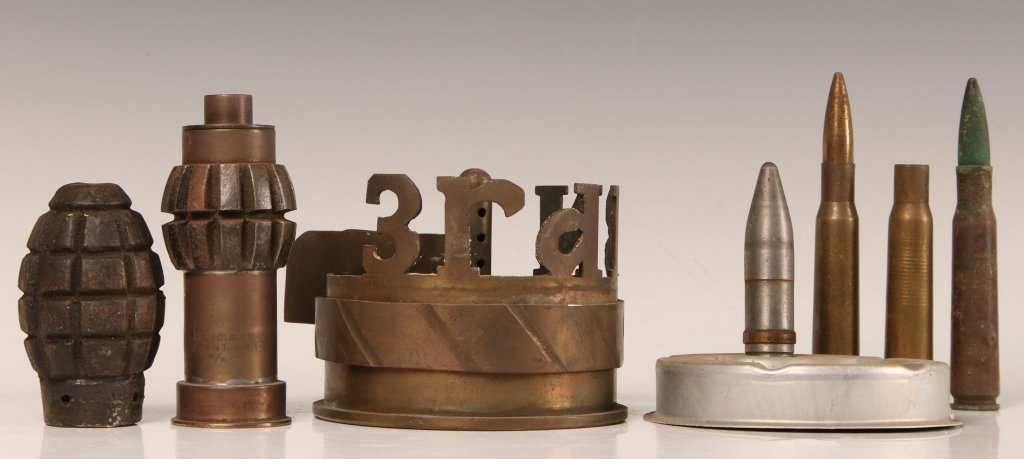 SEVEN PIECE MILITARY ORDNANCE COLLECTION: Lot consists of a 1944 105mm shell base that has been artfully crafted to read 'third battalion' in free standing letters along the edge and has a rest for cigarettes and matches, very unusual trench 