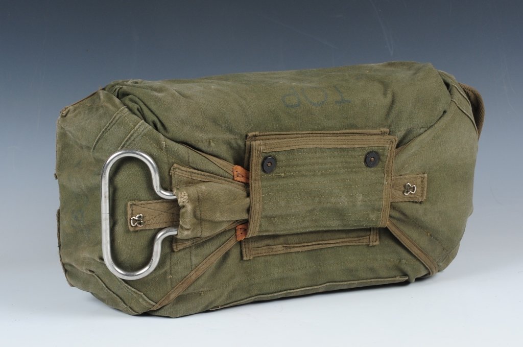 VIETNAM AIRBORNE CHEST RESERVE PARACHUTE: Green canvas body with nickel finish D ring rip cord, well marked 1966 dated. Snap hooks for attaching parachute harness on backside. Has been packed with foam rubber for display purposes. ​We a