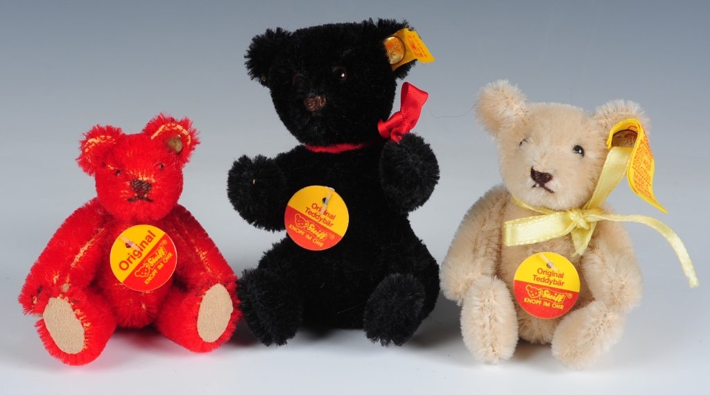THREE MINIATURE STEIFF TEDDY BEARS: Red teddy bear 039058 with button in ear, no ear tag, chest hang tag and catalog present, measures 2.75 inches sitting. Steiff cream teddy bear 0212/10, button in ear with yellow tag, chest hang tag, 