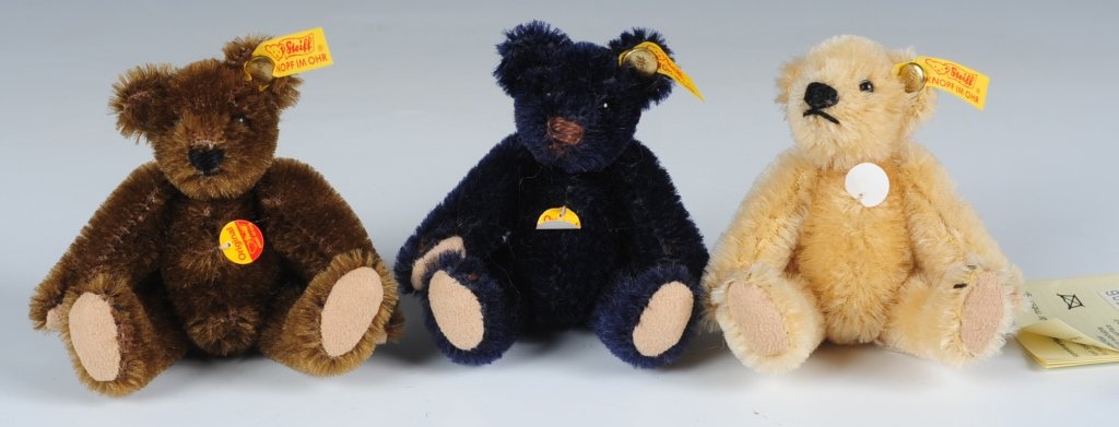 THREE MINIATURE STEIFF TEDDY BEARS: Mini bears in dark brown, light blond and navy blue, buttons in ears with yellow tags, chest hang tags, one with catalog, measure 2.5 inches sitting.