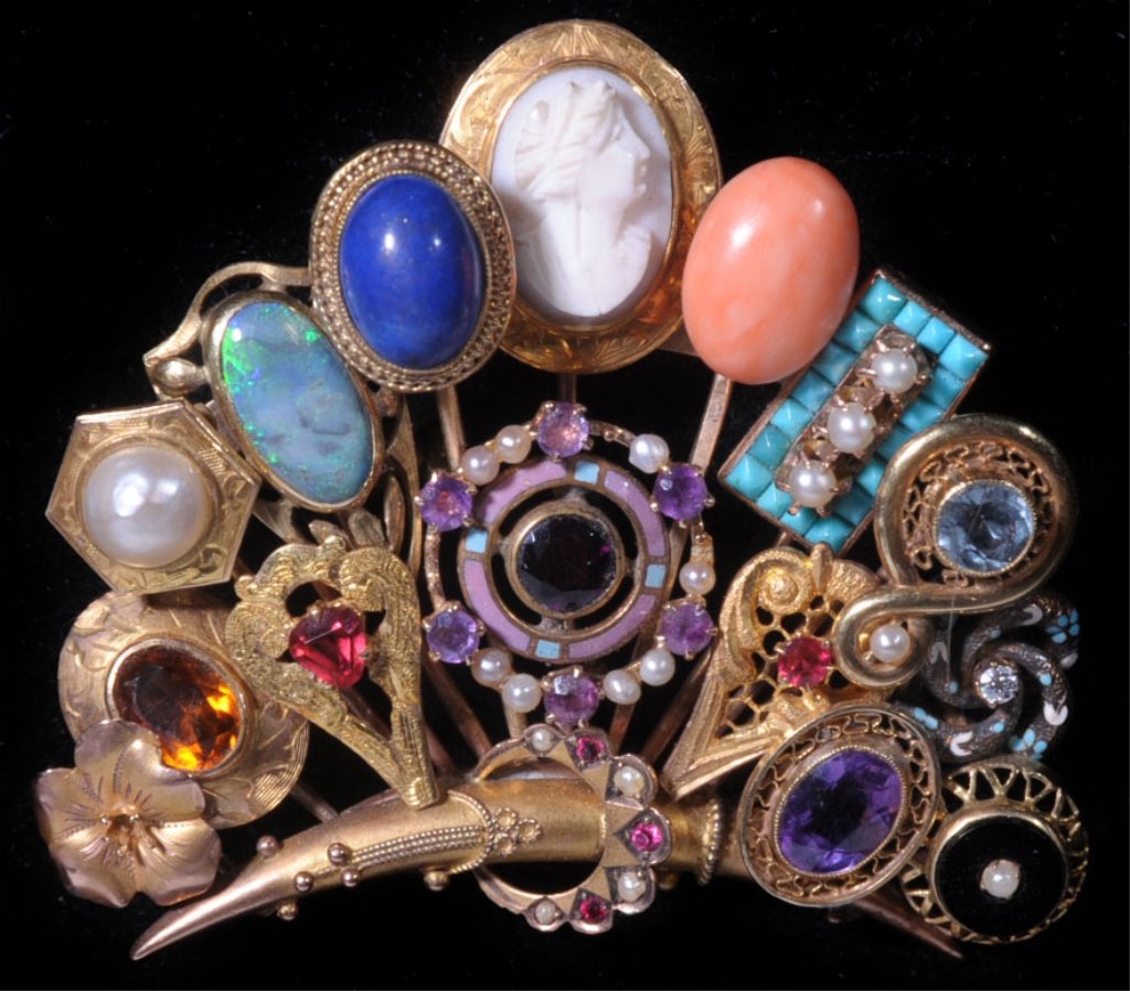 A 9KT BROOCH COMPRISED OF 16 ANTIQUE STICK PINS: Pearl, amethyst, opal and other semi-precious stones, coral cameo etc. Marked 375 on the mounting, measures 2.25 x 2 inches. Weighs 27 grams.