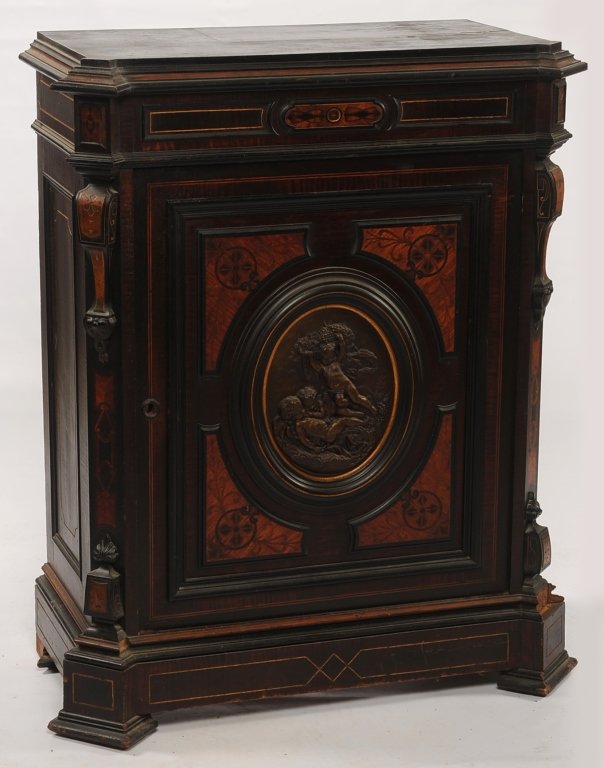 AMERICAN RENAISSANCE CABINET ATTR POTTIER AND STYMUS: Inlaid and ebonized side cabinet with central bronze plaque in the door. Measures 44 x 36 x 18 inches. ?We are happy to offer in-house shipping for all but very large or very fragile items. Some inter