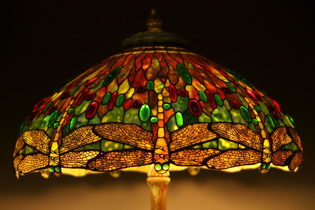 A DRAGONFLY MOTIF JEWELED AND LEADED SHADE TABLE LAMP: A handmade jeweled and leaded glass dragonfly motif shade created by Richard A. Bennett Jr and mounted on a Tiffany Studios reproduction bronze base. Measures 31 inches high with a 23 inch diameter sh