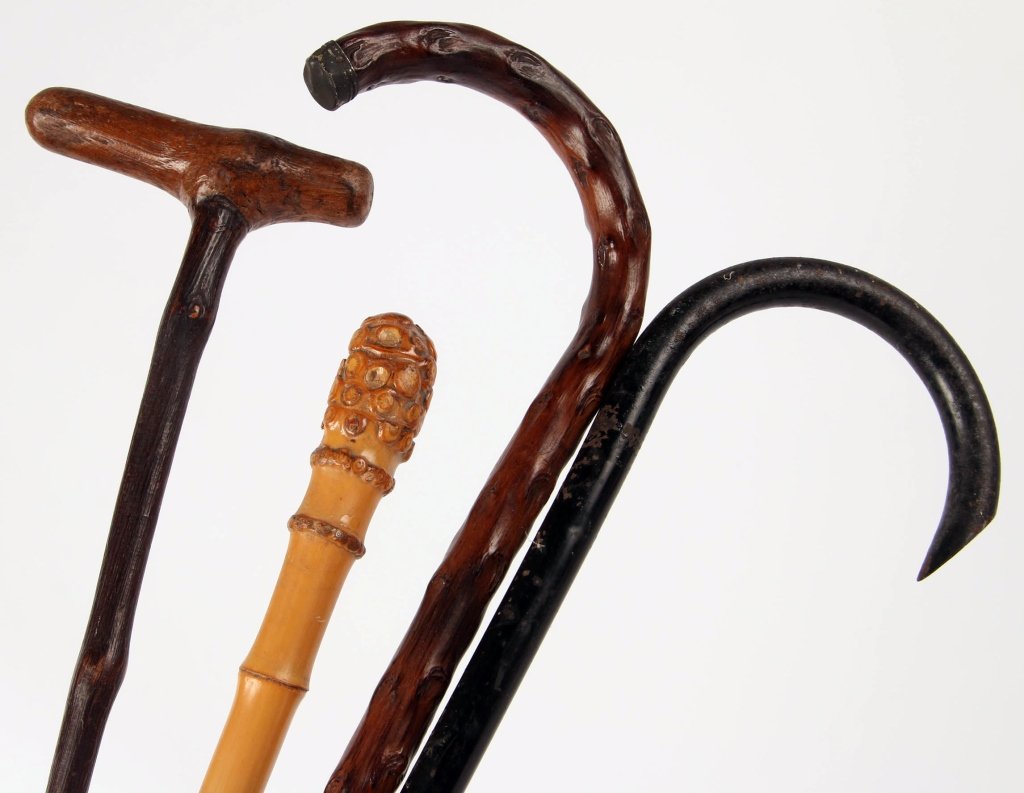 FOUR ANTIQUE CANES AND WALKING STICKS: Hollow iron cane with black paint, measures 36 inches, wear and light oxidation. Bamboo walking stick with a carved head and metal tip, measures 35.5 inches, good. Curved wooden cane with natural knot