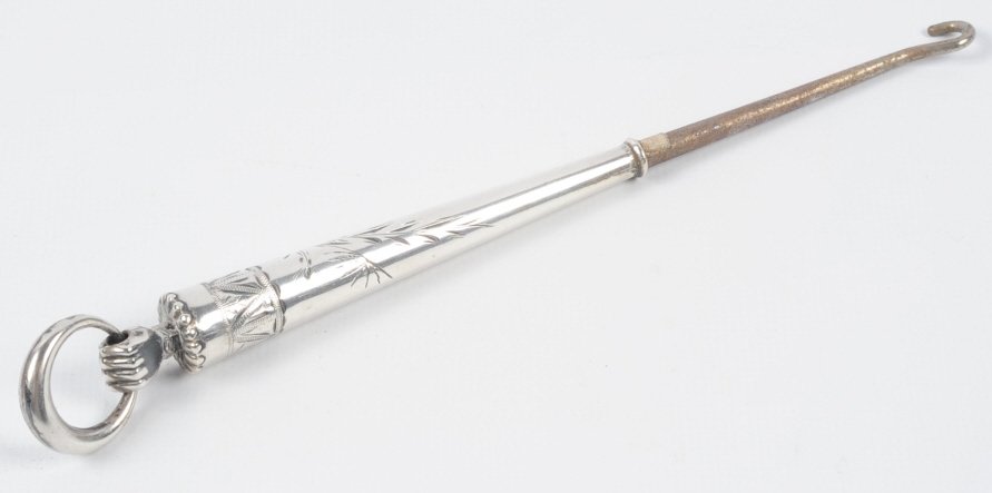 ANTIQUE STERLING BUTTON HOOK WITH HAND AND RING: A hand at the top holds a movable ring, hand chased designs, marked sterling, measures 7.25 inches. This lot is not from the Mundwyler-Moulthrop estate. We are happy to offer in-house shipping for all